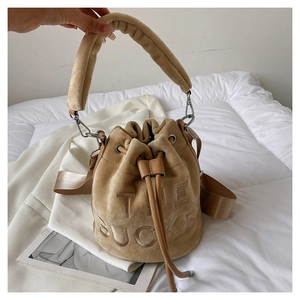 Detail of khaki velvet bucket bag featuring embossed THE BUCKET text and drawstring closure