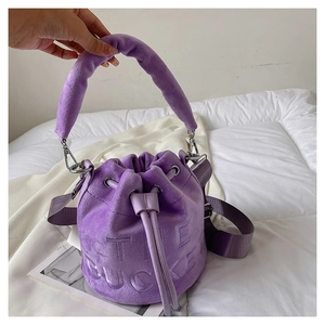 Detailed shot of purple plush bucket bag with THE BUCKET lettering and drawstring