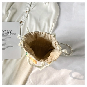 Top view of woven bucket bag featuring floral accents and a premium pearl chain strap