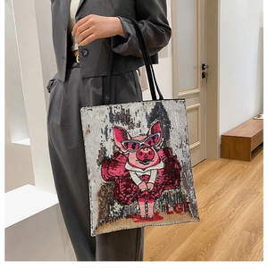 Model wearing a large silver sequin tote bag with a cartoon pig embroidery detail