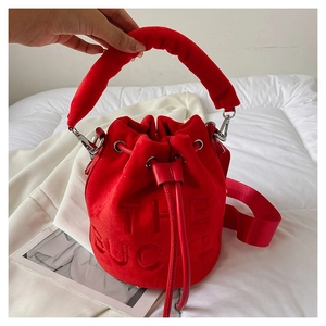 Detailed view of red plush bucket bag with The Bucket embossed lettering on soft velvet