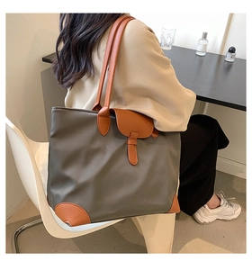 Detail of a large capacity tote bag featuring nylon fabric and leather reinforced corners