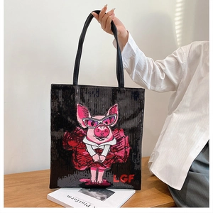 Detail of black sequin tote bag featuring pink pig embroidery and leather handles