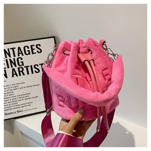 Detail of rose pink plush bucket bag with The Bucket embossing and nylon strap