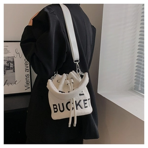 Detail of white canvas bucket bag with THE BUCKET lettering and drawstring closure