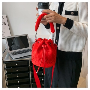 Close-up of bright red velvet bucket bag with The Bucket embossed lettering and plush handle