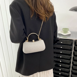 Elegant silver glitter evening clutch with gold metal handle and chain strap on a black blazer