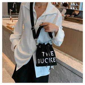 Close-up of black velvet drawstring bucket bag with white letter print and silver hardware
