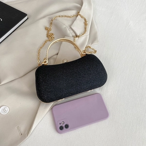 Elegant black glitter evening bag with gold handle and chain next to a smartphone