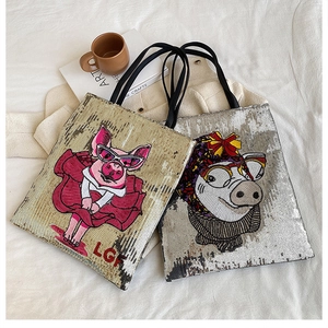 Detail of sequined tote bags with cartoon pig embroidery and black woven handles