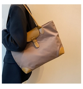 Side view of a large brown nylon tote bag with leather handles shown on a model