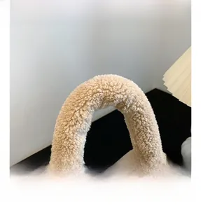 Détail de la poignée en peluche douce du sac seau marron montrant la texture duveteuse