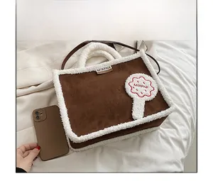 Detailansicht der braunen Wildledertasche mit weißem Lammfellbesatz und Markenlogo