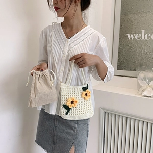 Handmade white crochet bucket bag featuring yellow sunflower accents and pearl strap