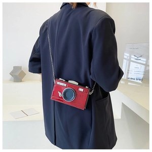 Detail of red vintage camera-shaped crossbody bag with silver chain on blue blazer