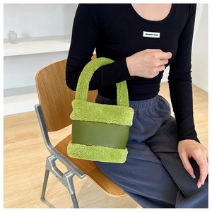 Détail d'un sac seau en peluche verte aux textures mixtes dans un intérieur douillet