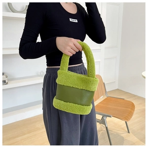 Détail du sac à main en peluche verte avec empiècement en cuir et poignée arrondie