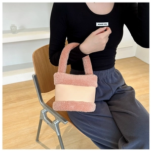 Détail d'un sac à main en peluche rose poudré et beige porté par un mannequin