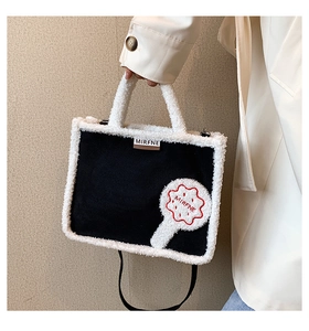 Detail of black canvas tote bag featuring white faux shearling trim and brand logo