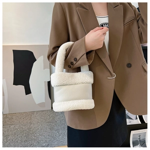 Détail de l'épissage en laine d'agneau blanche sur un mini sac seau tenu par un mannequin
