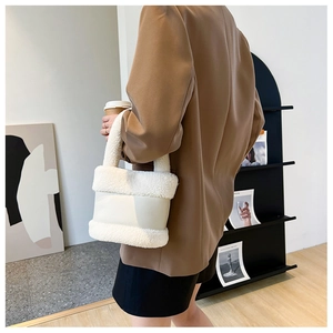 Détail d'un sac seau blanc en fausse fourrure avec une bandoulière contrastée et texture douce