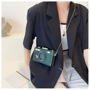 Detail of vintage camera shaped crossbody bag in dark green worn with elegant blazer