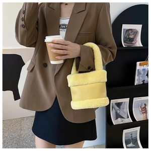 Détail du sac seau en peluche jaune avec bordure pelucheuse et contraste cuir sur modèle