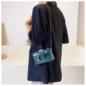 Detail of creative vintage camera-shaped crossbody bag in dark green patent leather