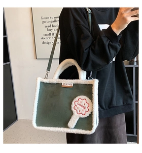Detailed view of large plush tote bag in dark green suede with white fleece trim details