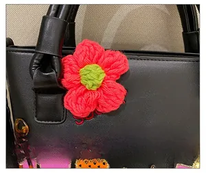 Detail showing crocheted floral charm and tortoise shell ring on a black bucket bag