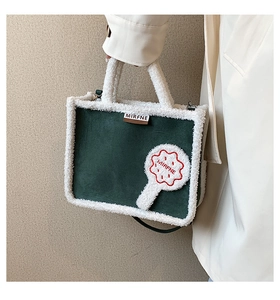 Detail of green suede tote bag with white faux fur trim and embroidered brand patch
