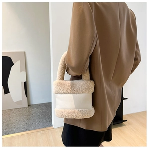 Détail du sac seau en peluche beige et blanc avec une veste de blazer marron chic