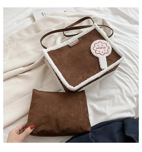 Detail of plush suede tote bag with faux fur trim, flower patch, and matching small pouch