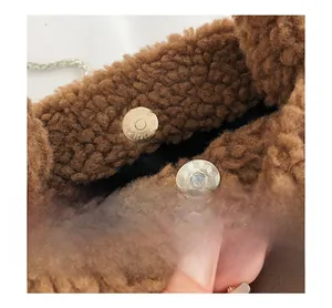 Detail of metal magnetic closure on brown fuzzy plush faux shearling bucket bag