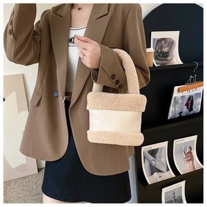 Détail du sac à main en peluche avec patchwork de cuir tenu par un mannequin en blazer