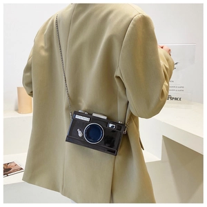 Detail of creative vintage camera crossbody bag with chain strap and glossy leather finish