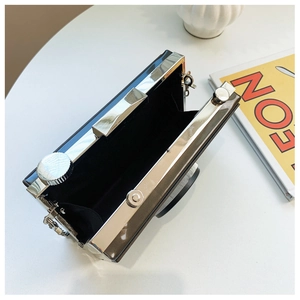 Detail view of the vintage camera-shaped clutch bag with black lining and metal frame