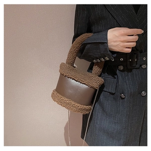 Detail of plush faux shearling trim on a brown leather bucket bag with chain strap