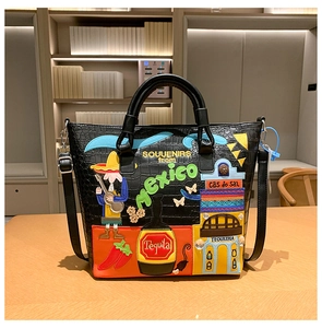 Detail einer schwarzen Kroko-Tasche mit bunter Mexiko-Stickerei auf einer Holzoberfläche