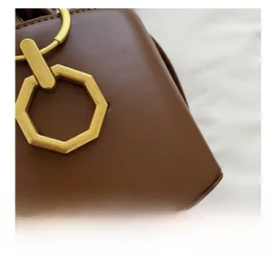 Detailed shot of brown matte leather handbag featuring vintage gold octagonal metal clasp