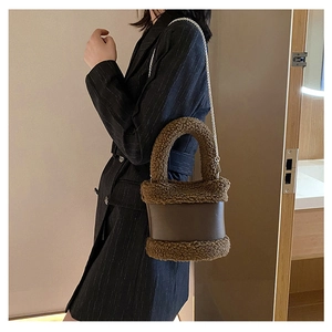 Detail of plush brown shearling bucket bag with smooth leather strap and silver chain