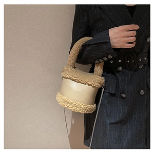 Detail of beige faux fur trim and smooth leather bucket bag with silver chain strap