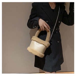 Close-up of cream PU bucket bag featuring brown faux fur trim and metal chain strap