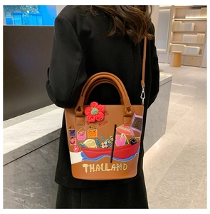 Detail of brown bucket bag with ethnic 3D embroidery and adjustable shoulder strap