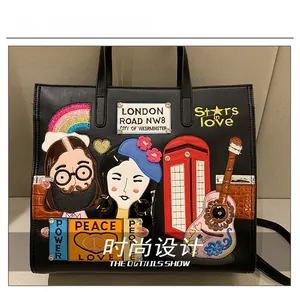 Detail view of black leather tote bag with London themed embroidery and guitar patches