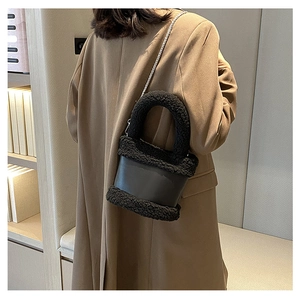 Detail of black plush bucket bag with silver chain strap shown on a model