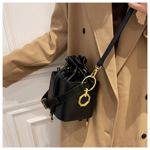 Close-up of black leather drawstring bucket bag with gold hexagonal rings on a model