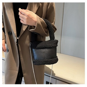 Detail view of black faux fur and leather bucket bag with silver chain on model