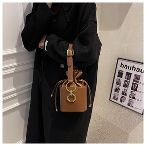Detail view of caramel brown bucket bag with gold octagonal buckle and drawstring design