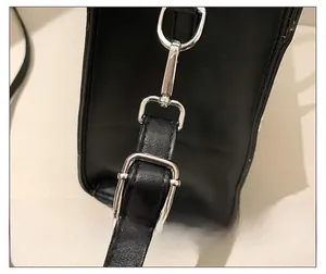 Detail of premium silver metal hooks and adjustable shoulder strap on a black tote bag